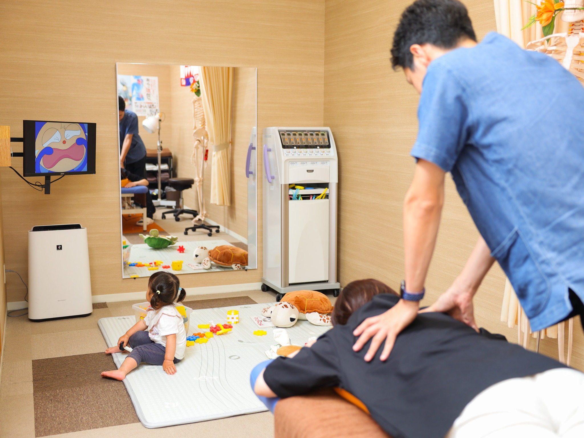 お子さまがキッズスペースで過ごすそばで、腰を施術する院長